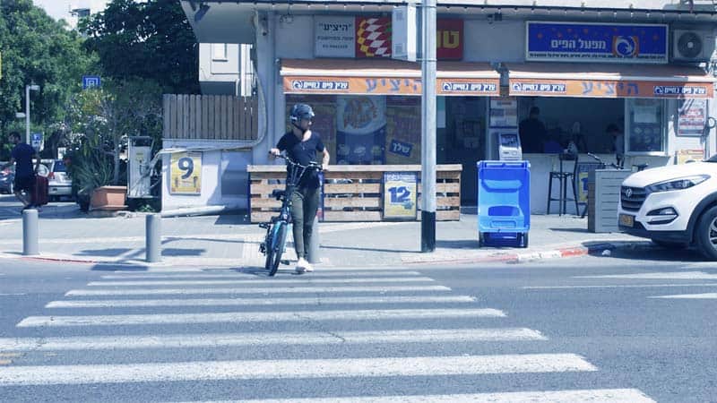 רוכב אופניים חוצה במעבר חצייה כשהוא מוביל את האופניים לצידו